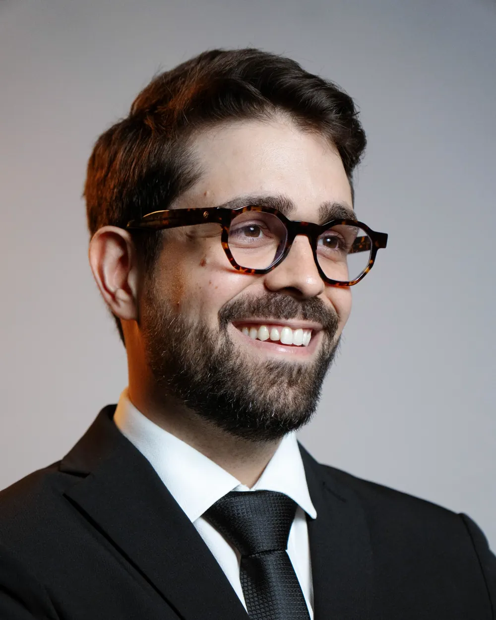 Dr. Mateus Capuzzo de terno, olhando para o lado