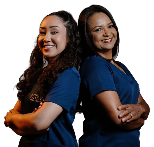 Jakellyne, à esquerda, e Selma, à direita, da recepção da clínica, de uniforme azul e sorrindo
